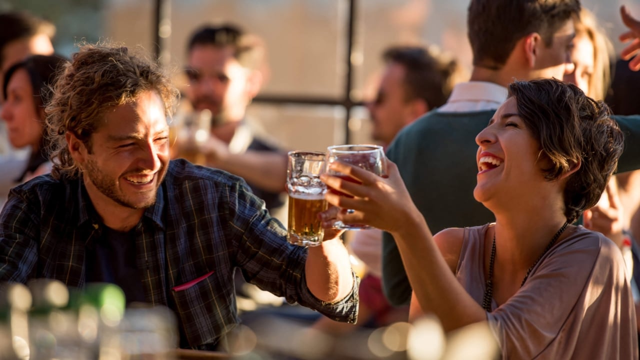 A man and a women laughing while drinking beer