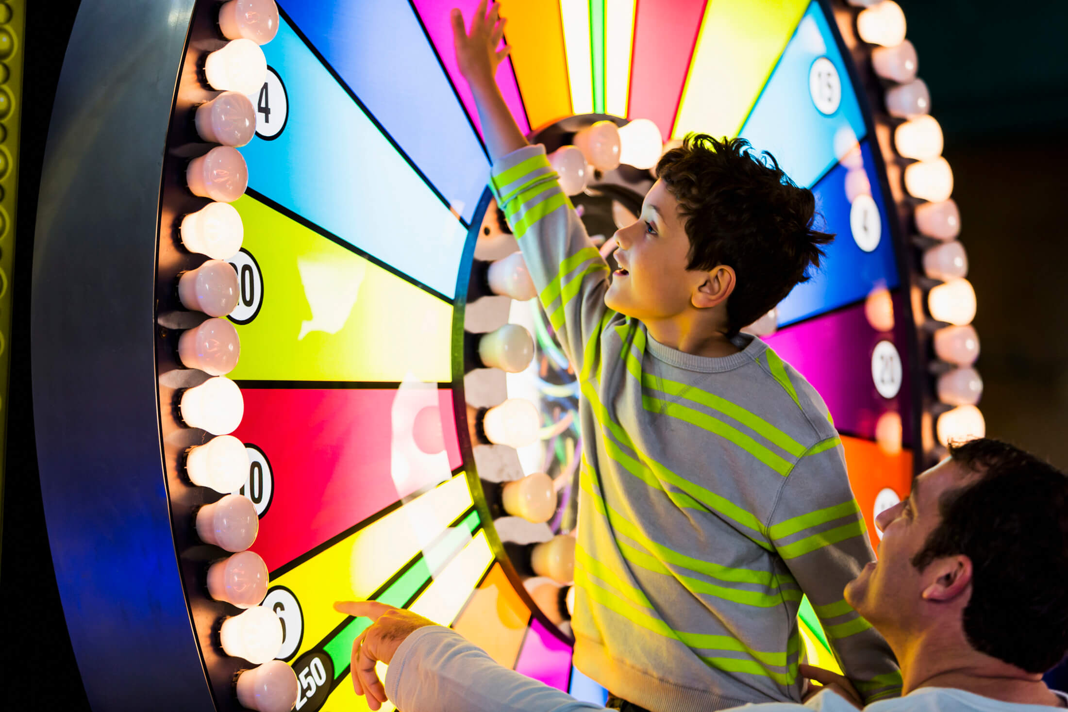 A child spinning a large glowing wheel in an arcade