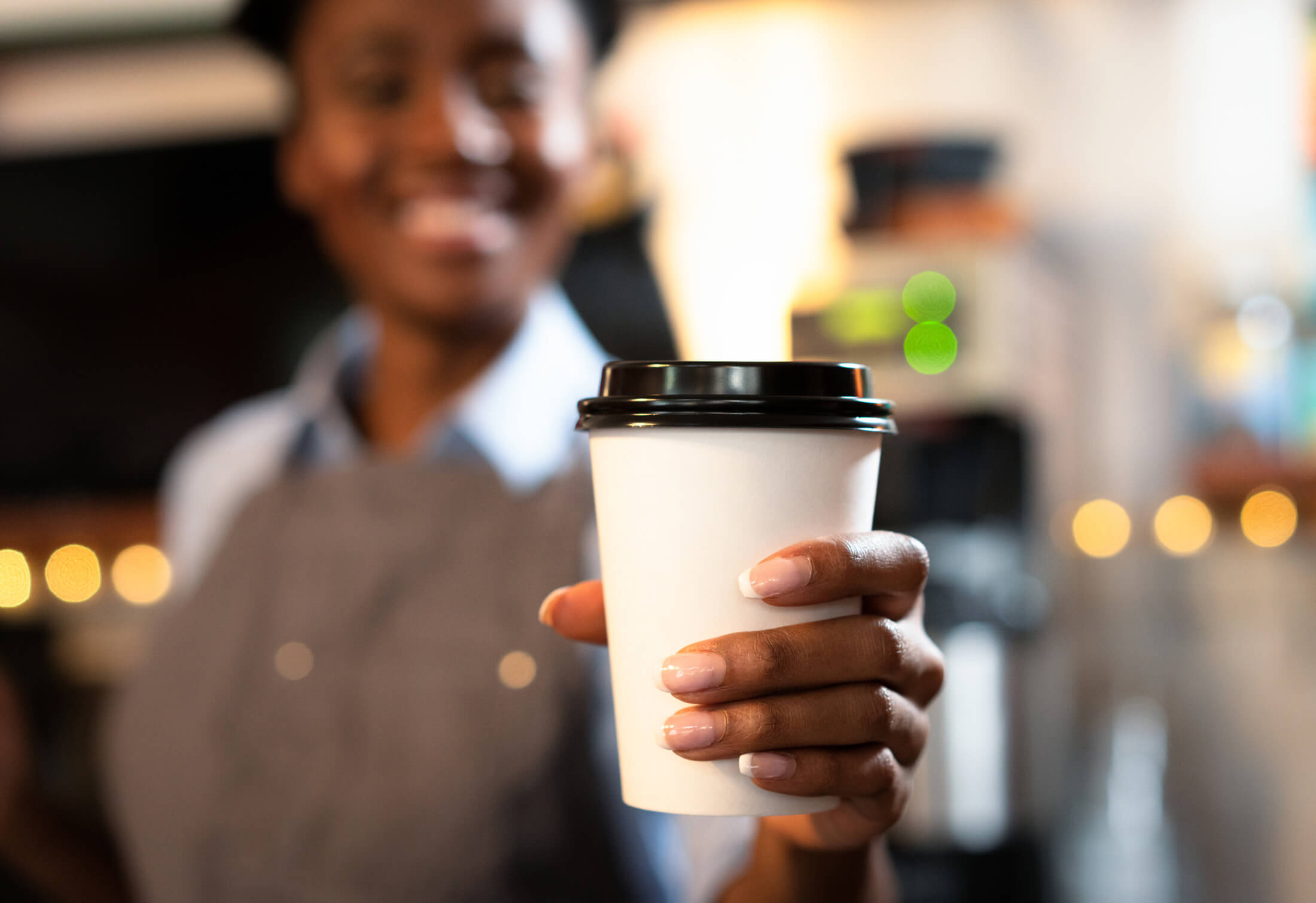 a woman holding a cup of coffee in a paper cup