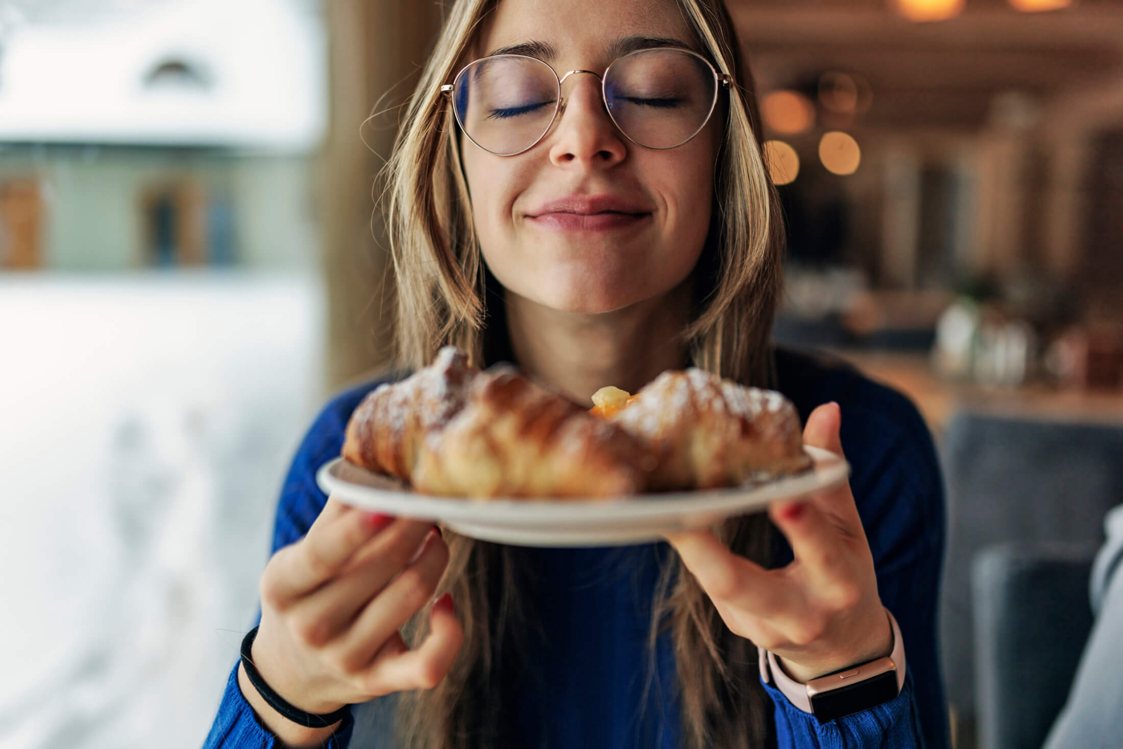 a women smiling and enjoying a croissant