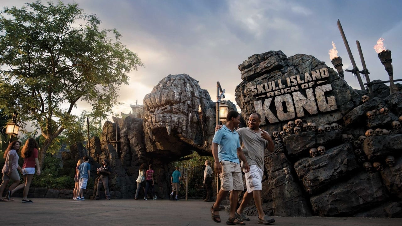 A father an his teenage sun outside the ride sign for the Skull Island, Reign of Kong ride