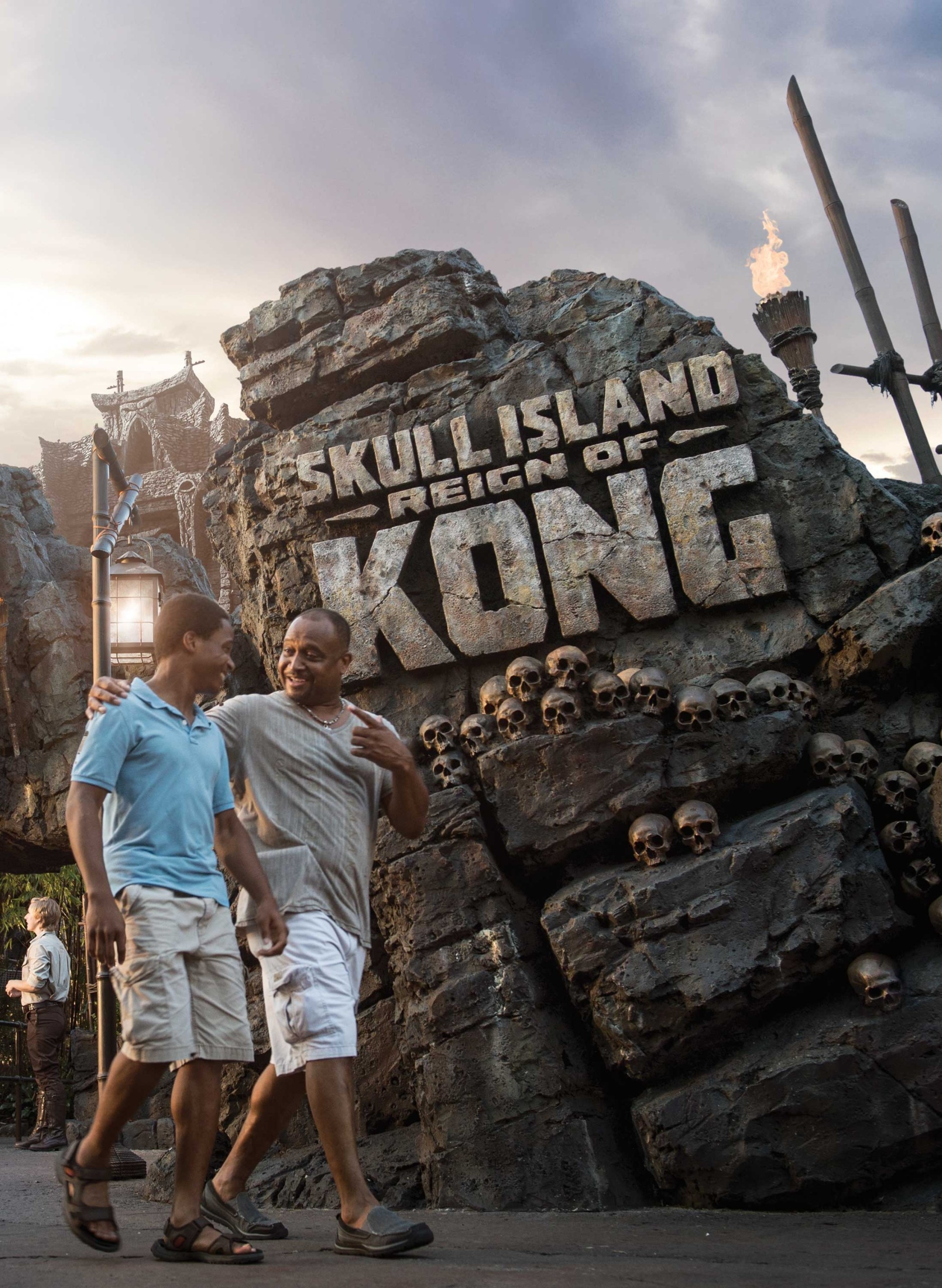 A father an his teenage sun outside the ride sign for the Skull Island, Reign of Kong ride