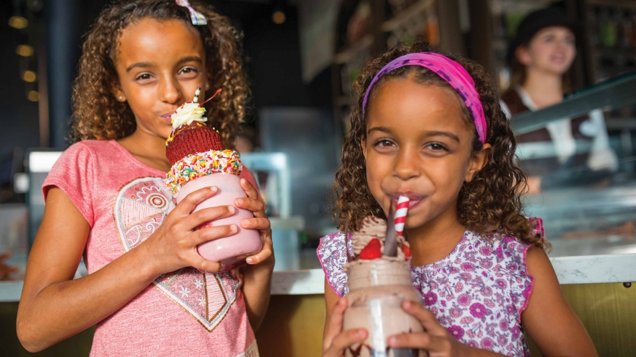 Two children enjoying extravagant milkshakes