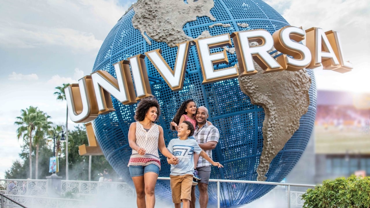 a family walking in front of the Universal Studios globe statue