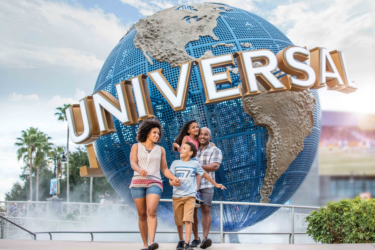 a family walking in front of the Universal Studios globe statue