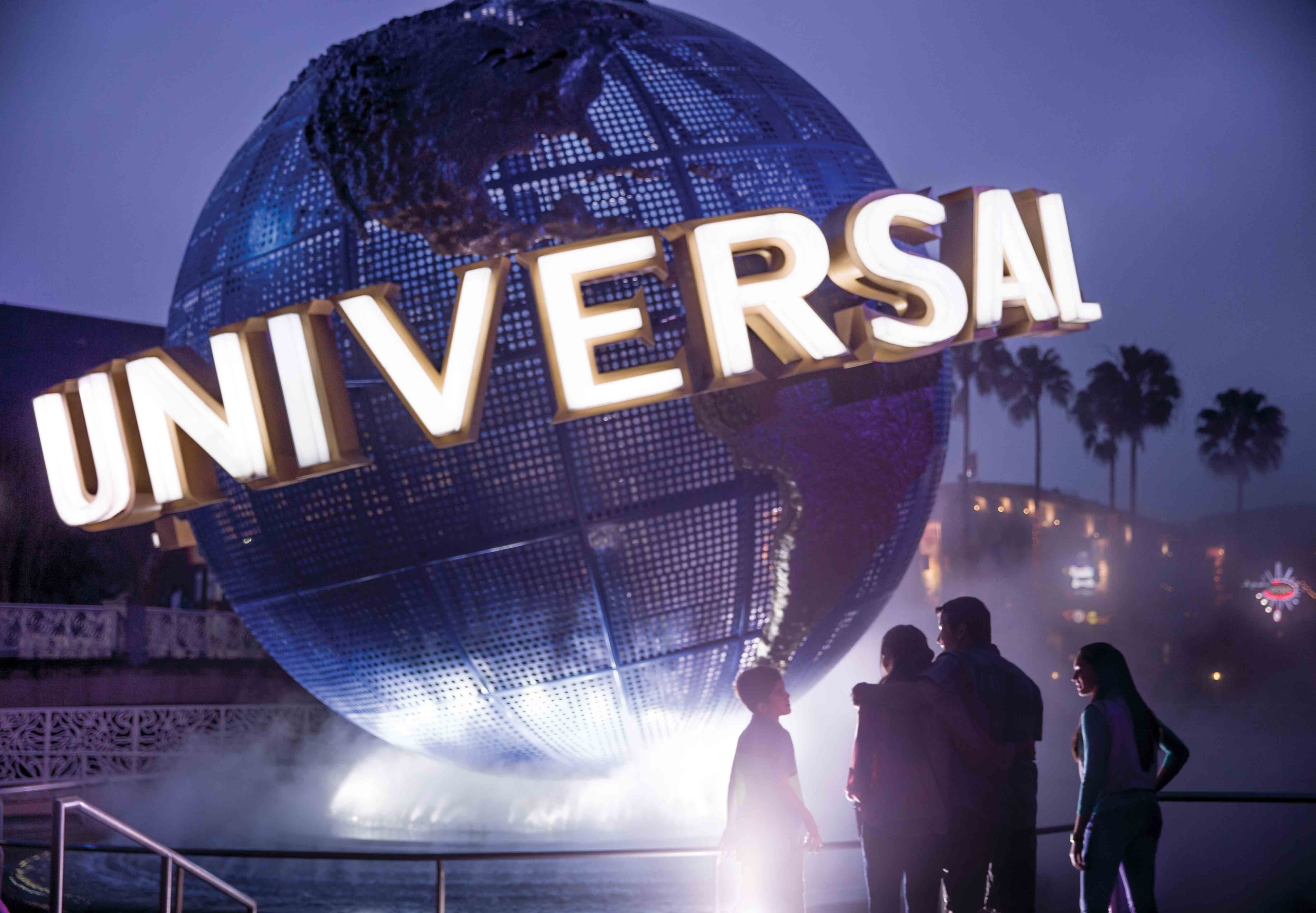 A family looking at the Universal Studios globe statue at night time