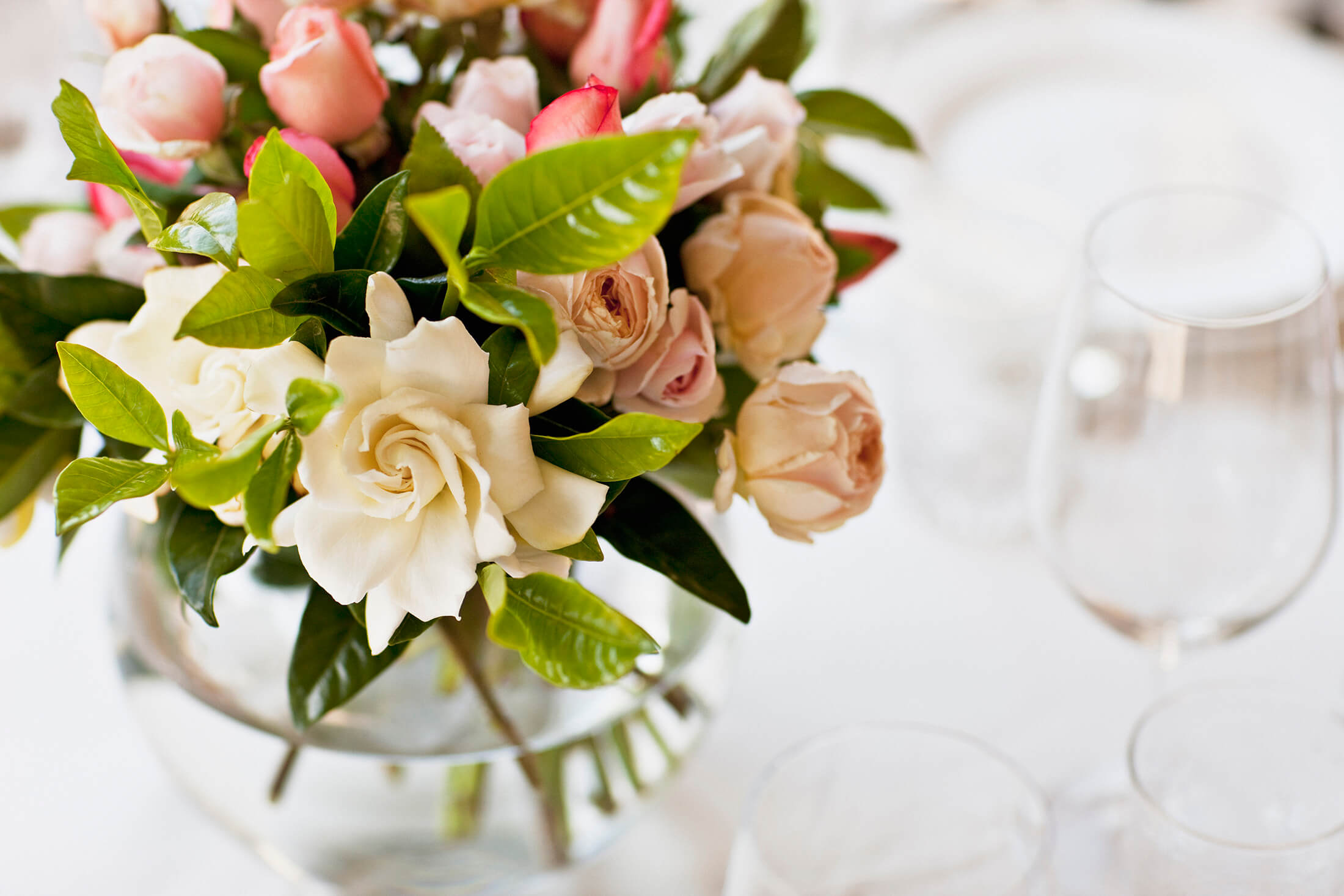 a table centrepiece with a bouquet of flowers and a wine glass