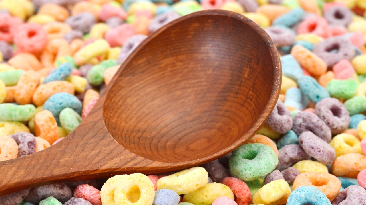 A wooden spoon surrounded by colorful breakfast cereal
