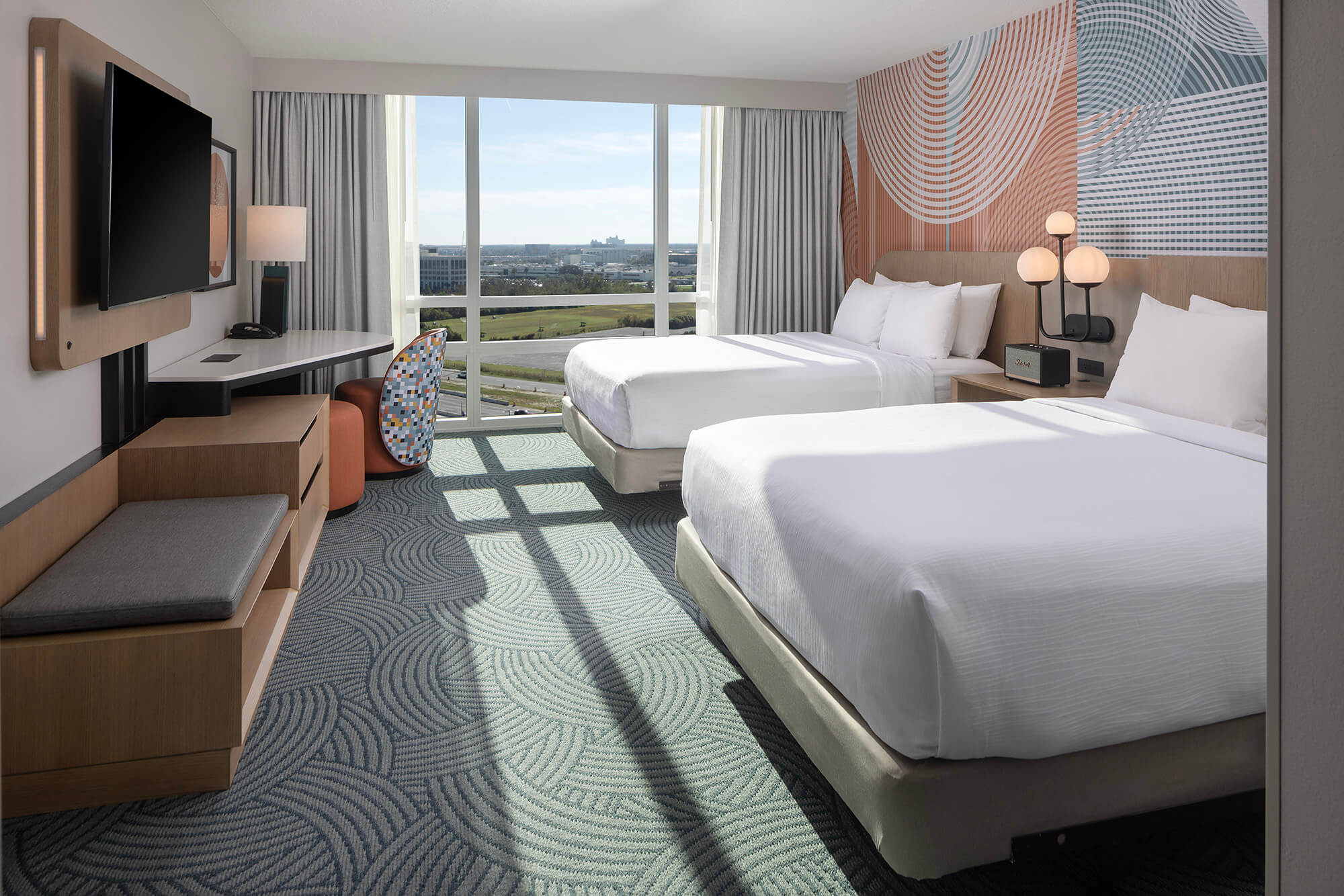 Two queen beds in a spacious room with a business desk area. At the back of the room is floor to ceiling windows