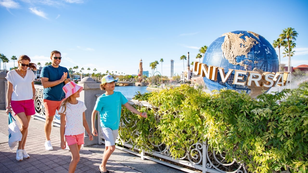 A father and two children exploring Universal Orlando theme park. In the background the Universal globe statue can be seen.