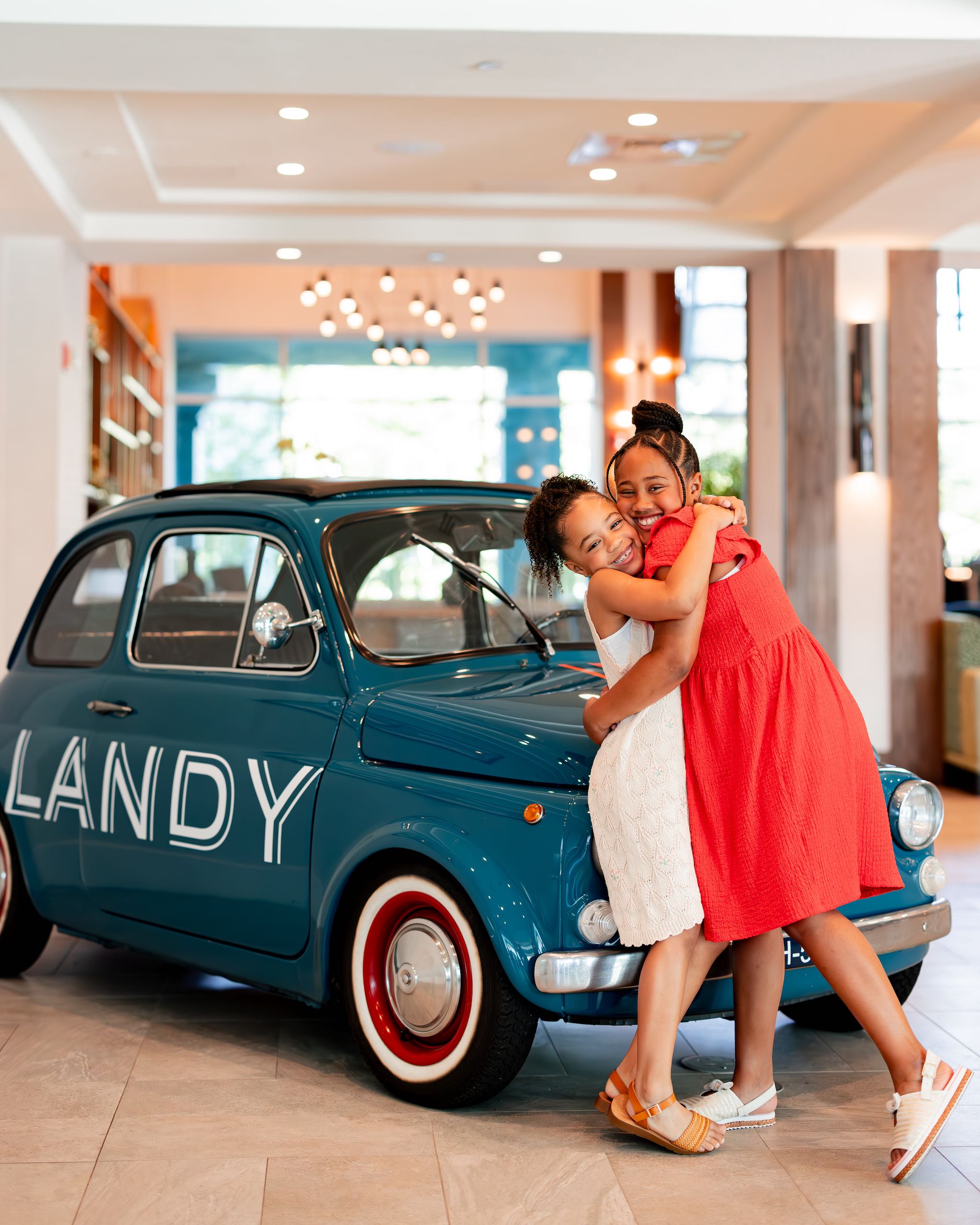 Sisters hugging in front of a small car