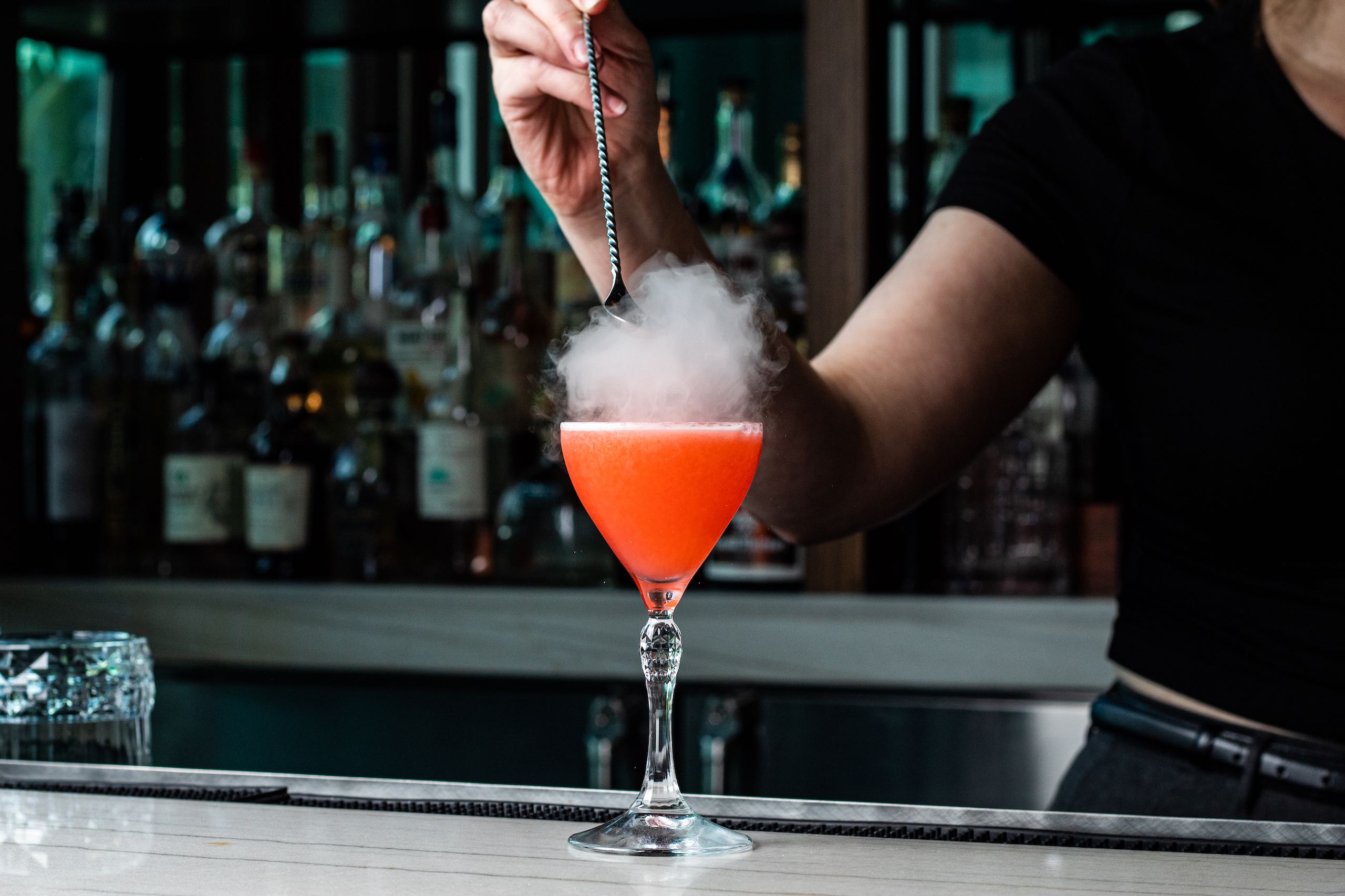 A bartender adding garnish to a drink