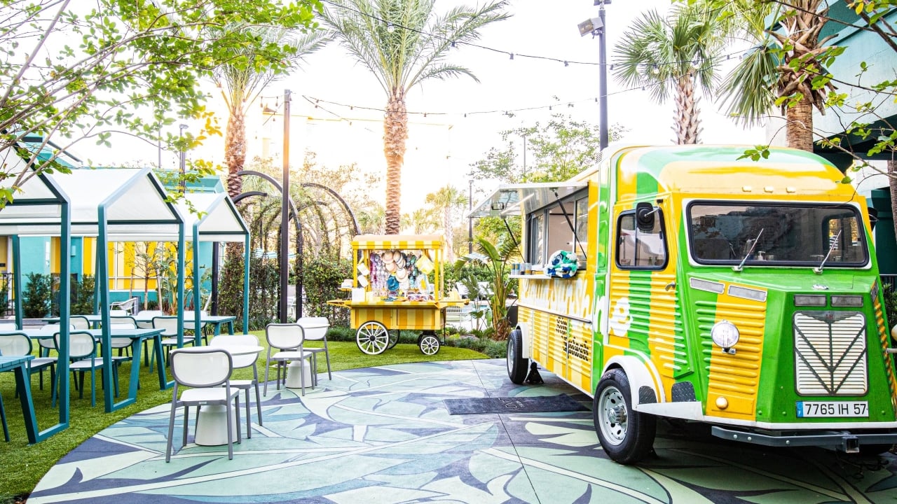 An outdoor sitting area with a food truck and a souvenir cart