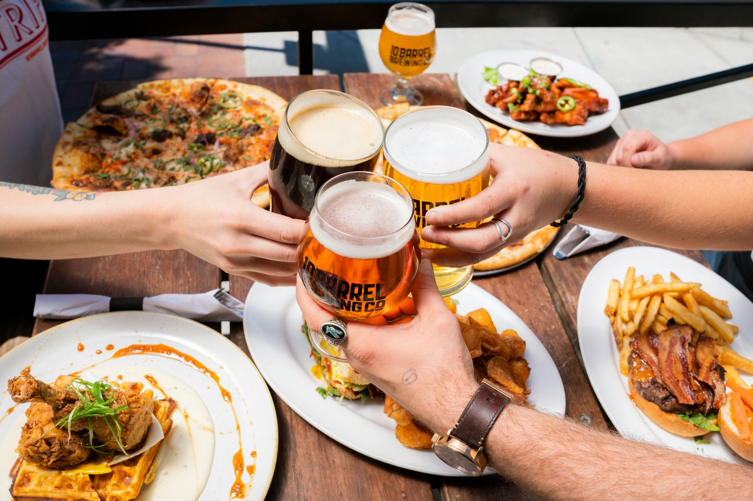 Three friends tapping their beer together in celebration