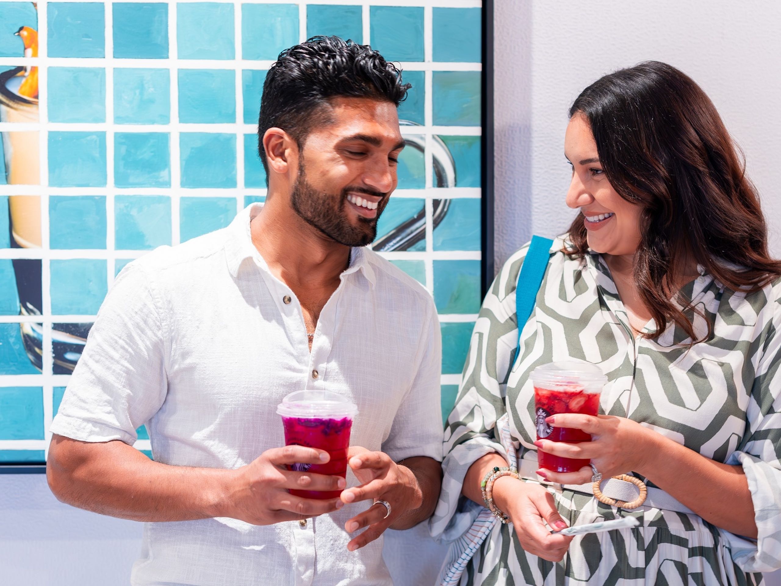 A couple laughing together while holding drinks