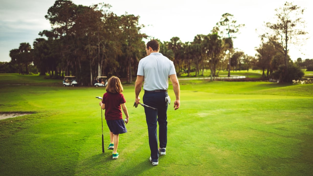 A man and child walking on a golf course